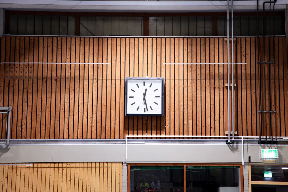 Badminton-Spieler in einer Sporthalle beim Training, mit mehreren Spielfeldern und Netzen im Hintergrund.